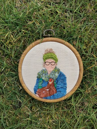 Portraitstickerei von einer Frau mit Brille, die ein Huhn im Arm hält