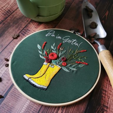 Stickbild von rotem Blumenstrauß in gelben Gummistiefeln mit Spruch "Bin im Garten!"